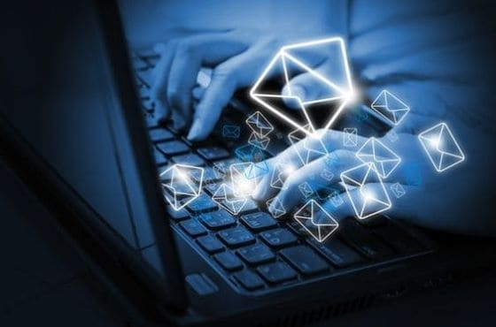 Manos escribiendo en un teclado, con íconos de sobres digitales flotando alrededor, representando estrategias de email marketing para aumentar conversiones.